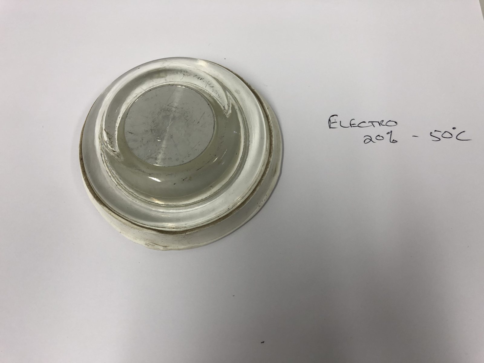 Lens photographed beside its handwritten process card: Electro 20% at 50 degrees C