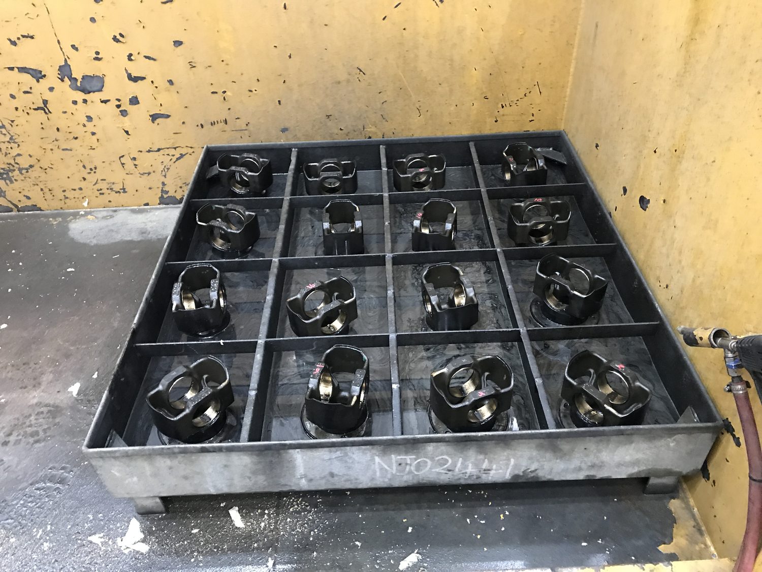 Twelve pistons loaded into a cleaning basket