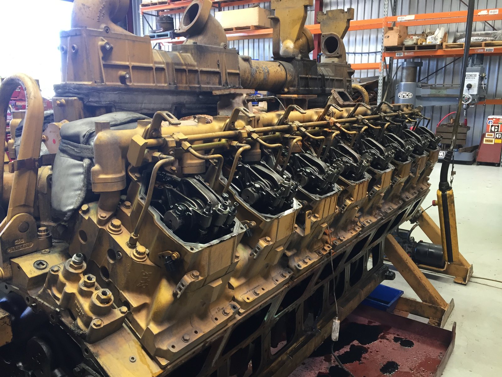 Caterpillar 3516 engine stripped on a stand with sixteen individual cylinder heads along the bank