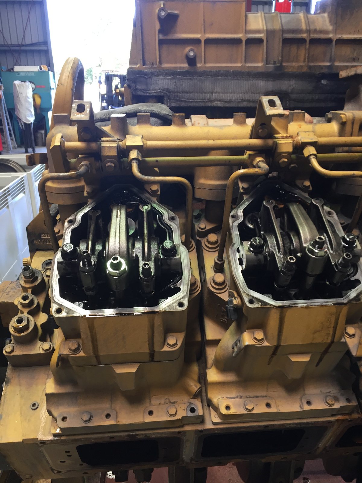 Two adjacent Cat 3516 cylinder heads, four studs each, valve gear exposed