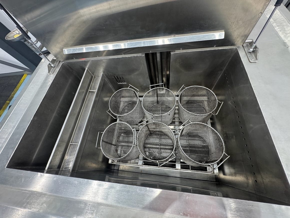 Baskets loaded with industrial parts going into an EVS 300 ultrasonic tank