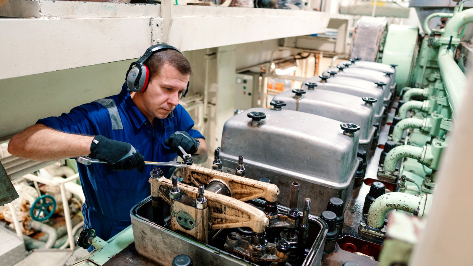 Engineer overhauling a marine diesel engine below decks