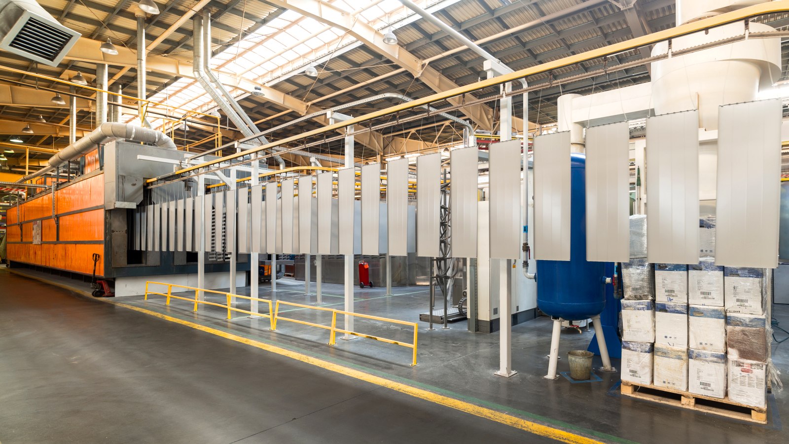 Powder coating line — panels on an overhead conveyor entering the curing oven