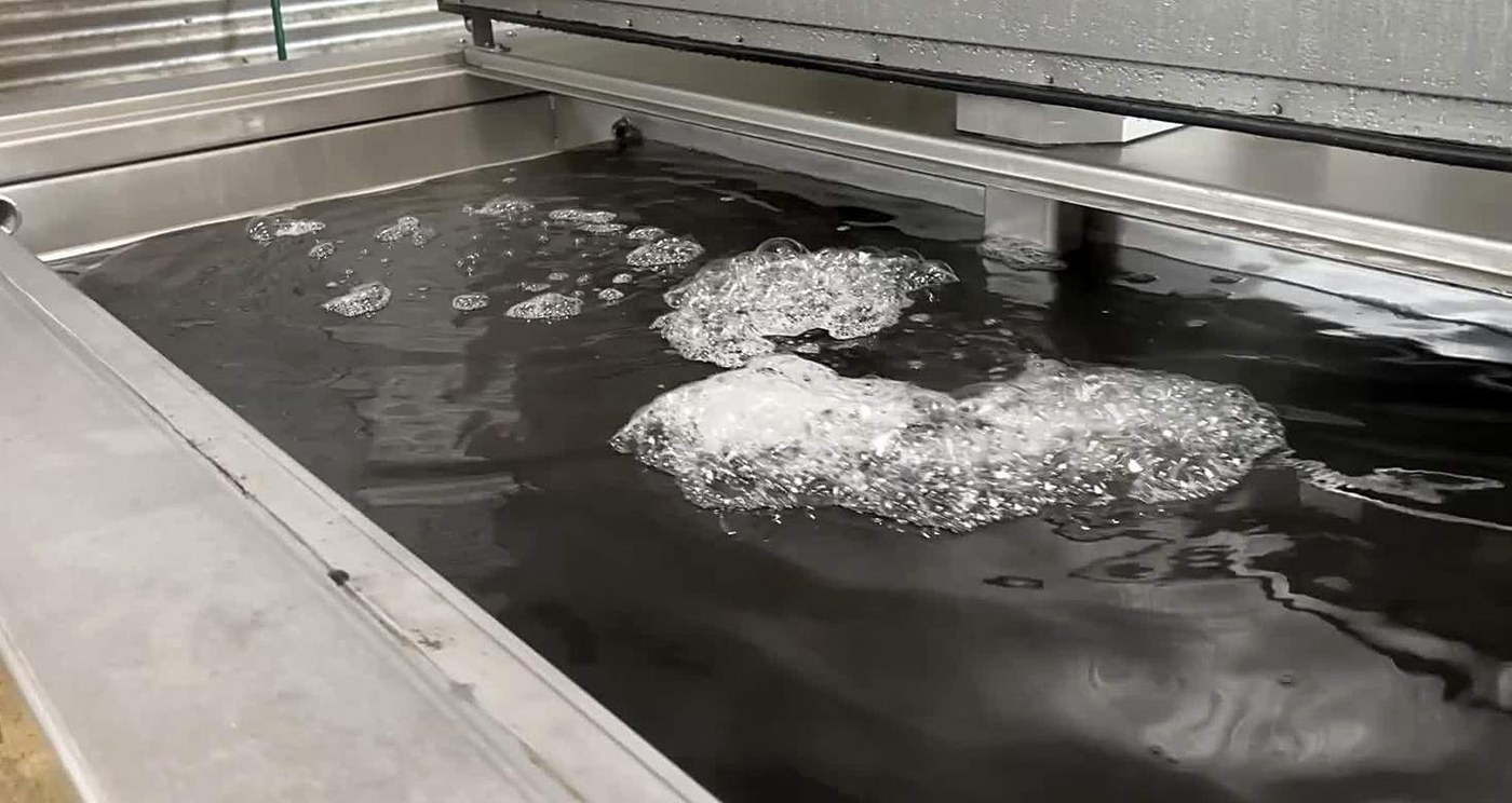 Cavitation clouds breaking at the surface of a working ultrasonic bath