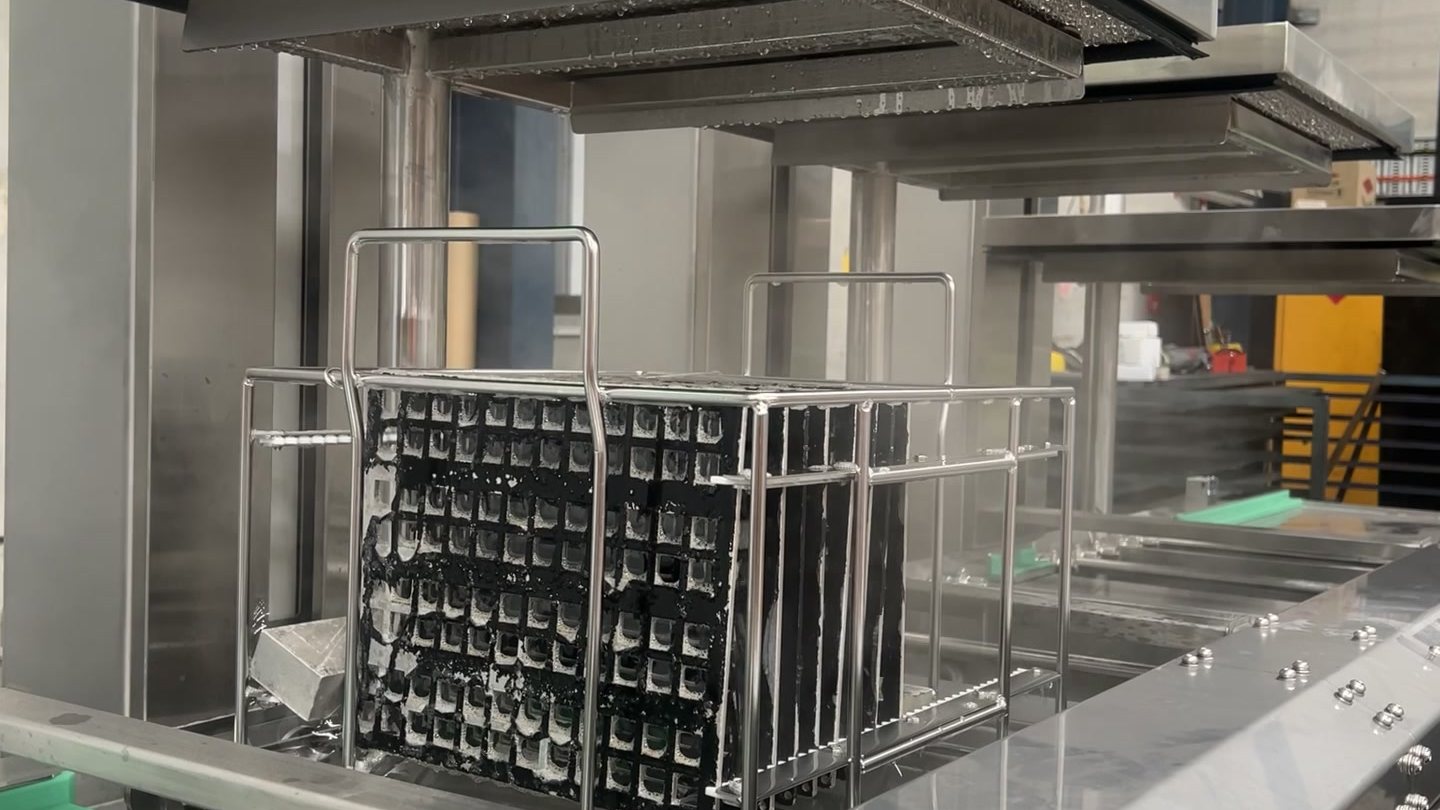 A rack of machined parts held above the ultrasonic wash tank of a Misonics Sonos L-130 line