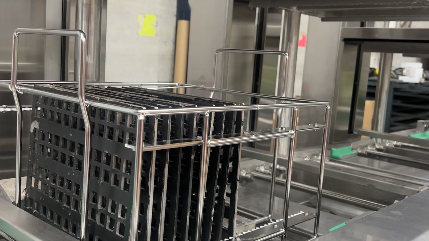 A rack of parts held above the ultrasonic wash tank of a Misonics Sonos L-130 line