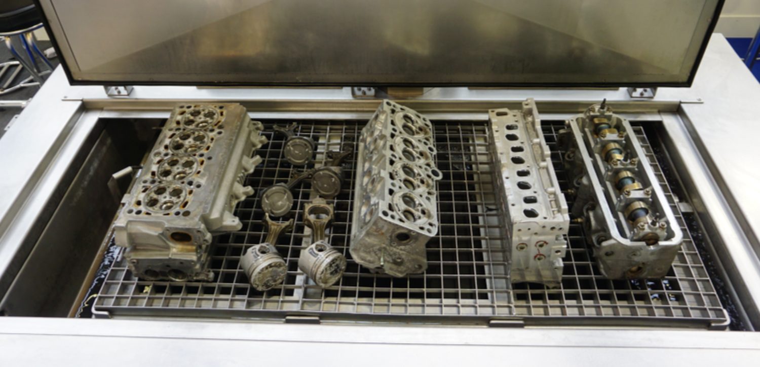 Cylinder heads, pistons and connecting rods loaded on the tray of an UltraTecno ACM ultrasonic cleaning machine