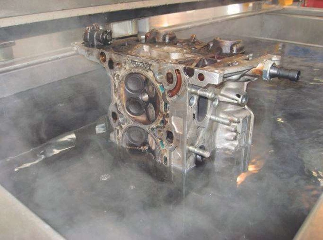 A cylinder block standing in an UltraTecno ultrasonic bath with steam rising off it