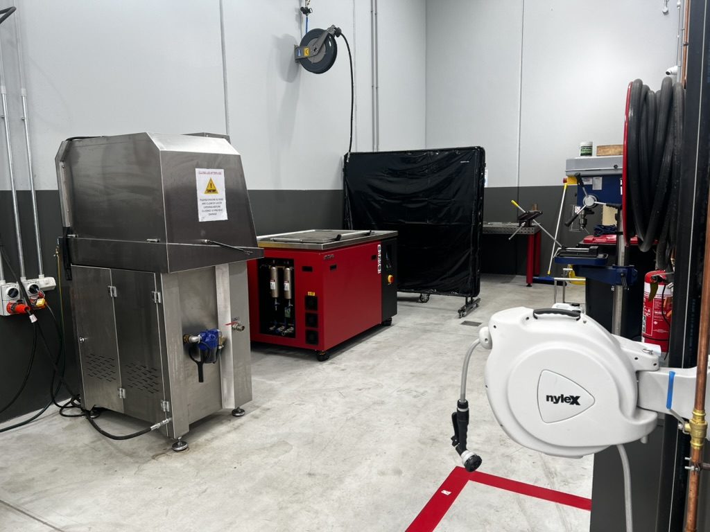 Misonics MSX 240 ultrasonic tank working beside a stainless spray parts washer in a workshop